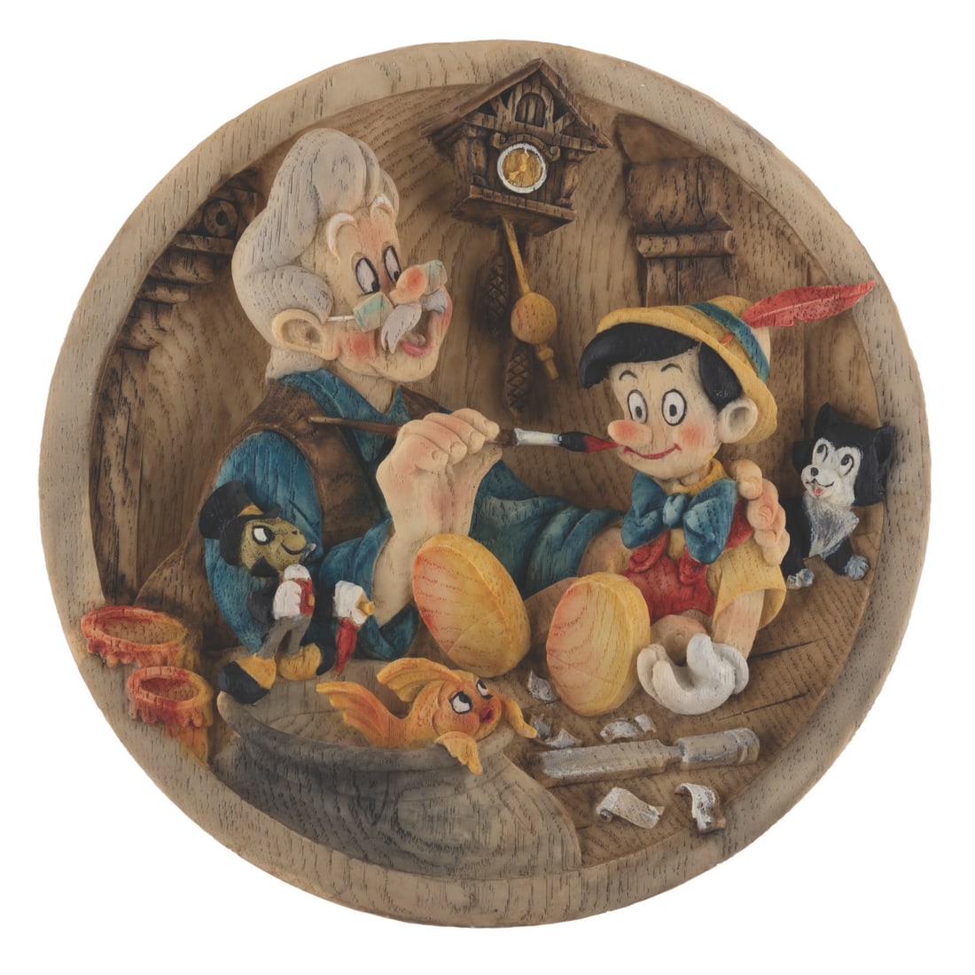 A "Pinocchio" and Geppetto 3-D Relief Plate.: (Disney, 1999) A "Pinocchio" decorative plate produced in Italy featuring a relief of Geppetto, Figaro, Cleo, and Pinocchio. The heavy resin plate is cast from a hand-carved wooden original sculpted