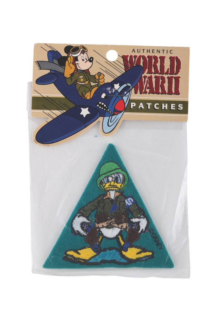 A Reproduction Donald Duck World War II Patch.: (Disney, 1990s/2000s) A reproduction World War II insignia patch of Donald Duck as a commando, sold exclusively at the Disney Parks. Measuring 3.5” x 3”, the patch is in fine condition, st