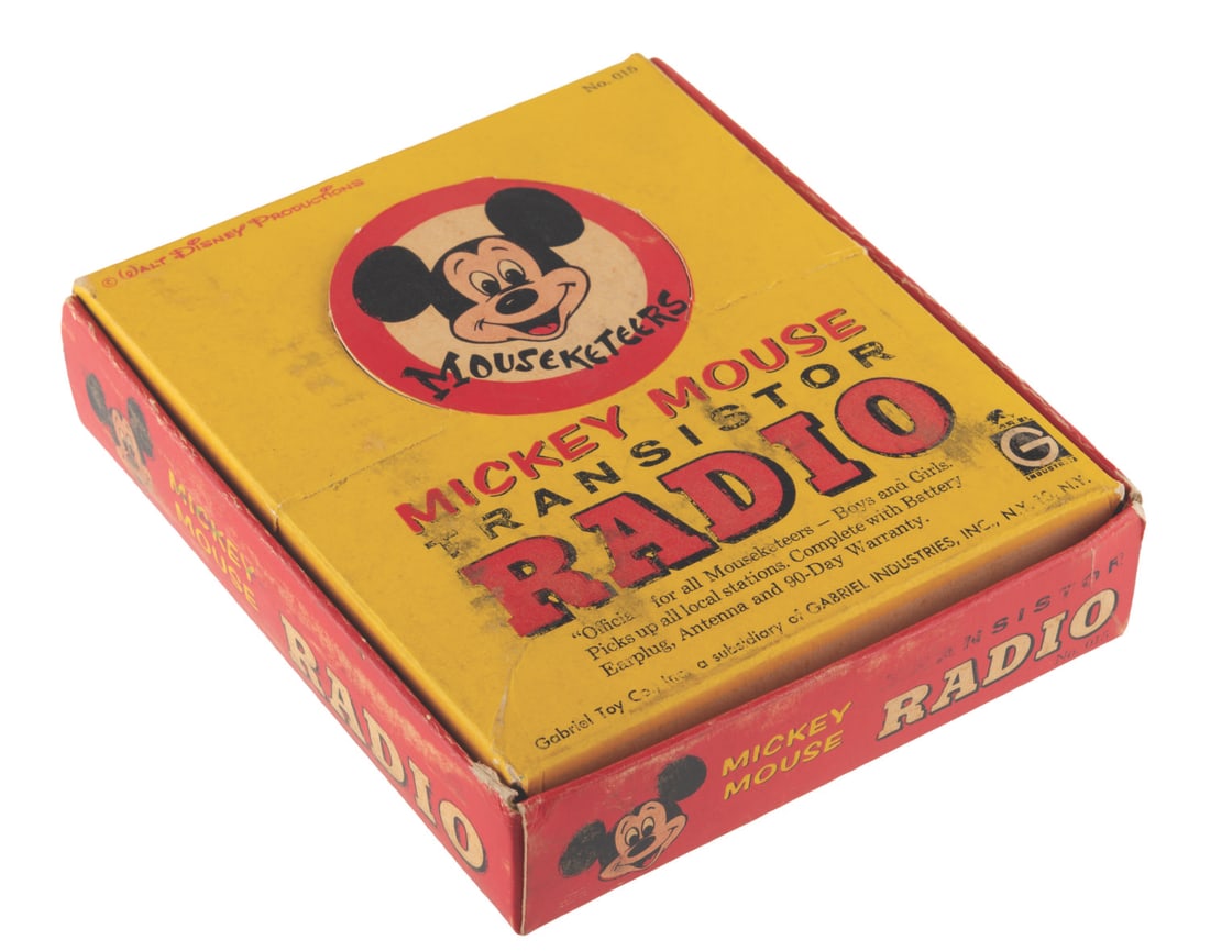 A Mousketeers Mickey Mouse Transistor Radio in Box.: (Gabriel Toy Co., 1960s) An Official Mouseketeers Mickey Mouse AM transistor radio with the original box, earplug, battery, warranty card, and detachable antenna. The radio powered on when tested,