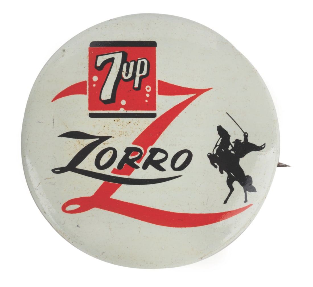A 7-Up Zorro Button.: (Disney, 1957) A rare button from a “Zorro” 7-Up promotion. Measuring just over 1” in diameter, the button is in very good condition with faint scratches and wear from use.