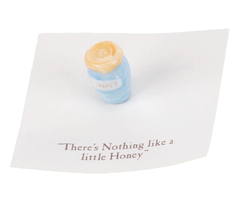A Mini "Winnie the Pooh" Blue Honey Pot Figurine.: (Michel and Co., 1990s) A mini "Winnie the Pooh" ceramic figurine of a honey pot inspired by the original illustrations for the books by E. H. Shepard. The figurine is attached to a card with a quote