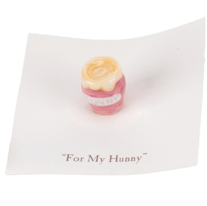 A Mini "Winnie the Pooh" Red Honey Pot Figurine.: (Michel and Co., 1990s) A mini "Winnie the Pooh" ceramic figurine of a honey pot inspired by the original illustrations for the books by E. H. Shepard. The figurine is attached to a card with a quote