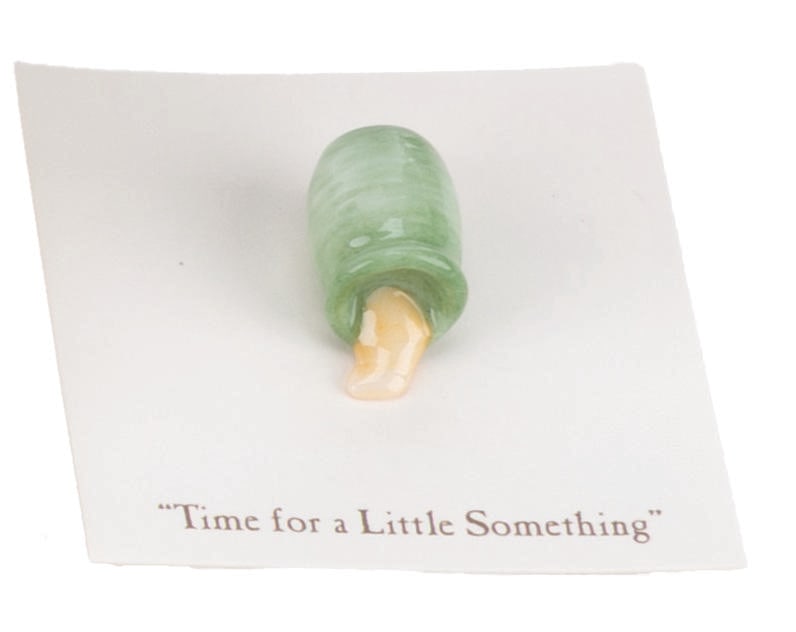 A Mini "Winnie the Pooh" Green Honey Pot Figurine.: (Michel and Co., 1990s) A mini "Winnie the Pooh" ceramic figurine of a honey pot inspired by the original illustrations for the books by E. H. Shepard. The figurine is attached to a card with a quote 