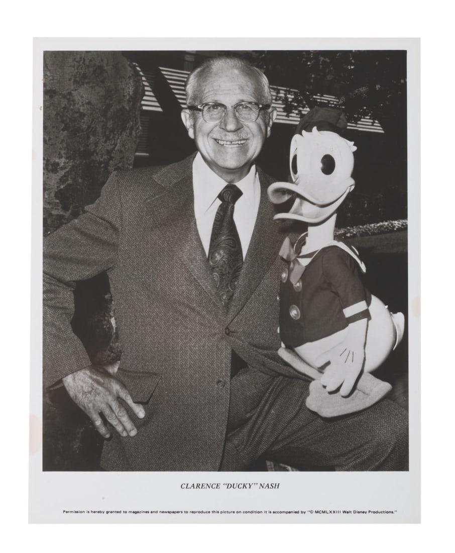 A Clarence "Ducky" Nash Photograph.: (Disney, 1973) A publicity photo of Clarence "Ducky" Nash, the original voice of Donald Duck, with his Donald puppet. Measuring 8" x 10", the print is in very good condition.