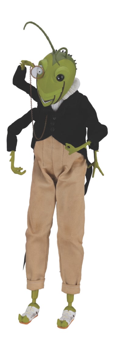 A “James and the Giant Peach?? Grasshopper Figure.: (Jun Planning, 1997) A vinyl figure of the Grasshopper from “James and the Giant Peach.” The figure features a cloth jacket and pants, and a metal chain for the monocle, with articulation to a