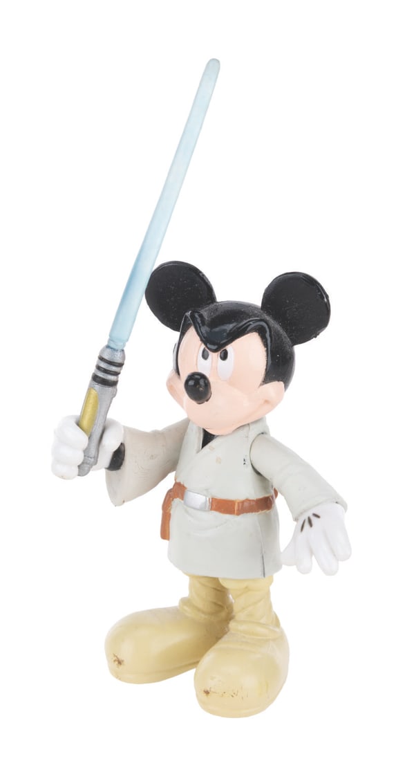 A Jedi Mickey Mouse Figure.: (Disney Parks/Lucasfilm, 2007) An action figure of Mickey Mouse dressed as a Jedi and wielding a blue lightsaber. Standing 2.5" tall, the figure is in good condition with light handling wear.