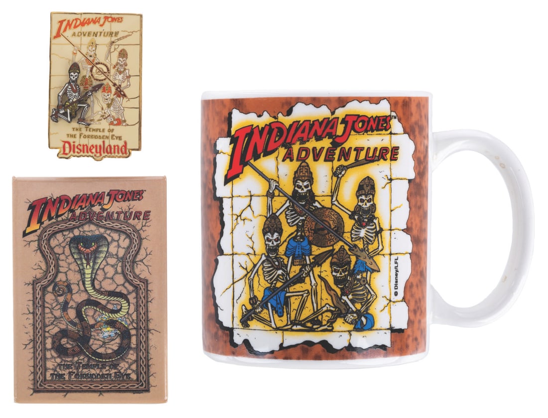 Three Early Indiana Jones Adventure Souvenirs.: (Disneyland, 1990s) A collection of Indiana Jones Adventure: Temple of the Forbidden Eye souvenirs from the early years of the attraction. Included are a snake button, a mug and a pin featuring the sk
