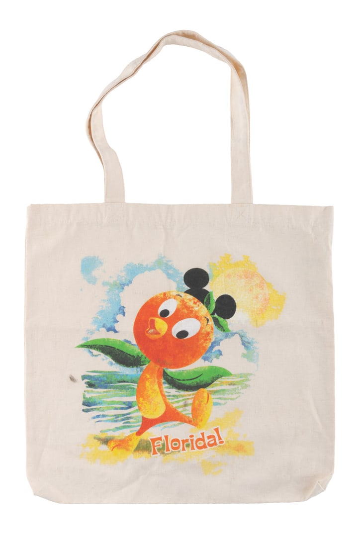 A Florida Orange Bird Tote Bag.: (Walt Disney World, 2010) A rare tote bag souvenir of Walt Disney World featuring the popular Orange Bird wearing a mouse ear hat on a beach. Measuring 14.5" x 14.25", the cotton bag is in very good c