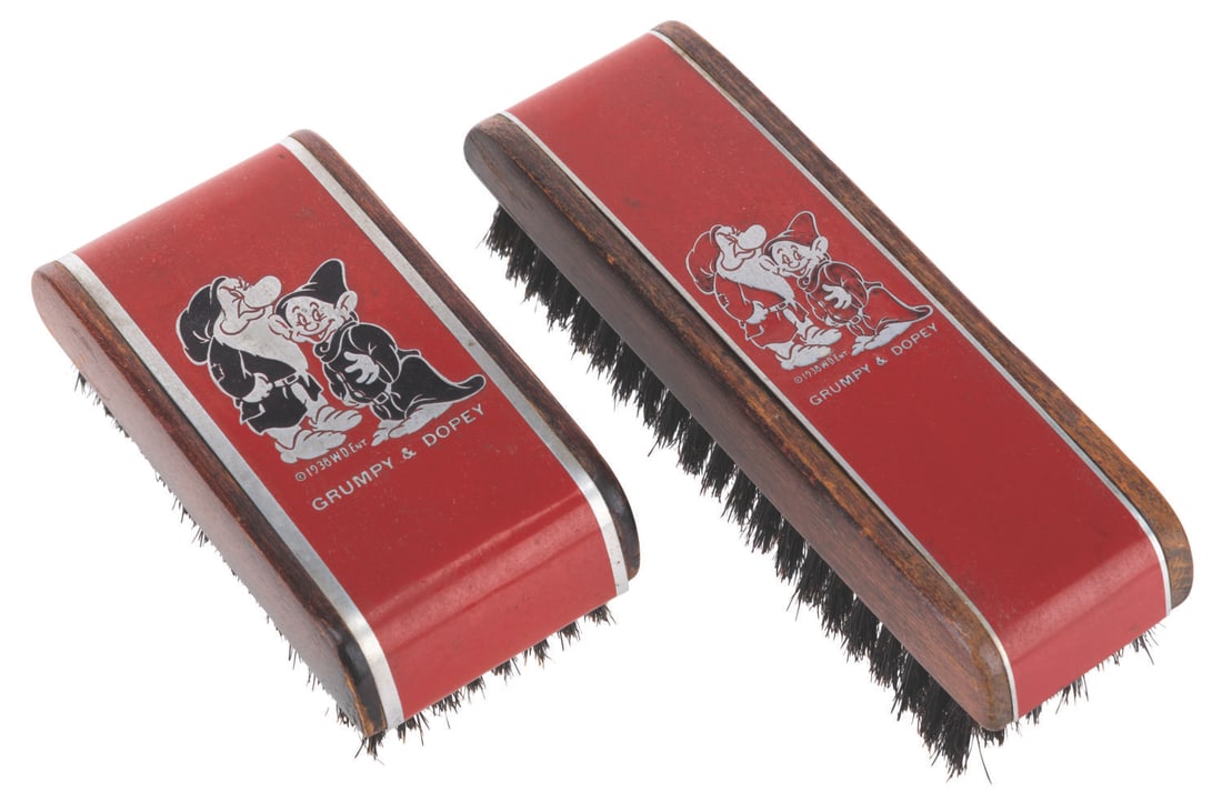 A Pair of "Snow White" Grumpy & Dopey Shoe Brushes.: (Henry L. Hughes Co., 1938) A pair of "Snow White and the Seven Dwarfs" Grumpy and Dopey wood and tin shoe brushes, featuring a Walt Disney Enterprises copyright. Ranging in size from 3.5" to 5"