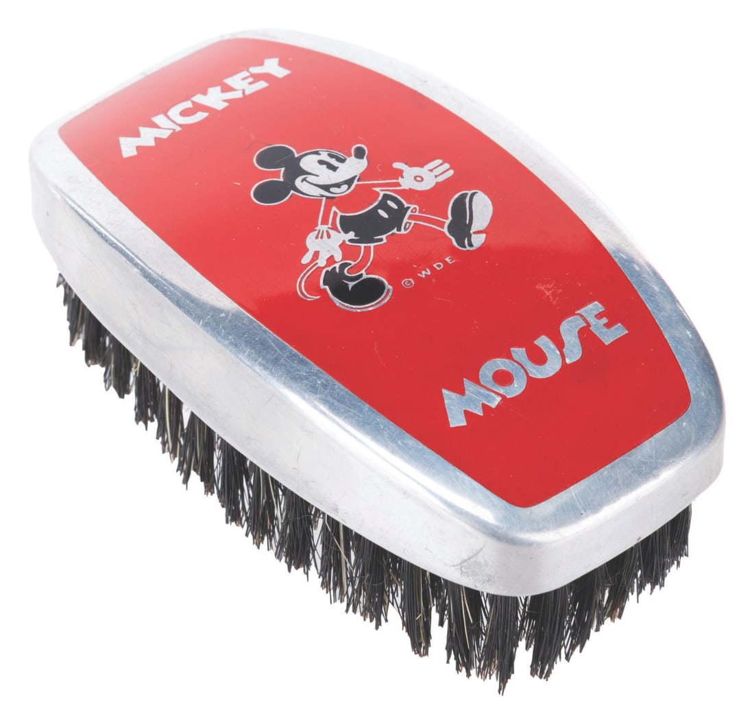 A 1930s Mickey Mouse Shoe Brush.: (Henry L. Hughes Co., 1930s) An early wood and tin shoe brush featuring Mickey Mouse and a Walt Disney Enterprises copyright. Measuring 3.75" x 2" x 1.5", the brush is in very good condition with