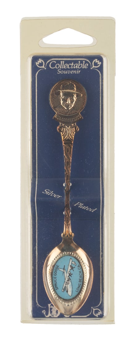 A Howard Hughes Spruce Goose Souvenir Spoon.: (1970s-90s) A collectible spoon featuring Howard Hughes and his legendary Spruce Goose. Measuring 4.75" long in its 2" x 0.75" x 6.25" original case, the spoon displays in very good condition with