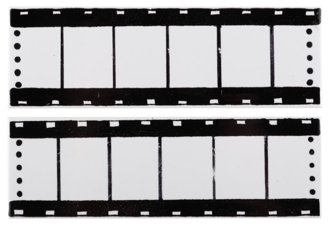 A Pair of Ceramic Tile Film Strips.: (Toon Tiles, 1990s) A pair of decorative tiles with a film strip design. These were samples for a potential merchandise item. Each measuring 6" x 2", the tiles are in very good condition with light