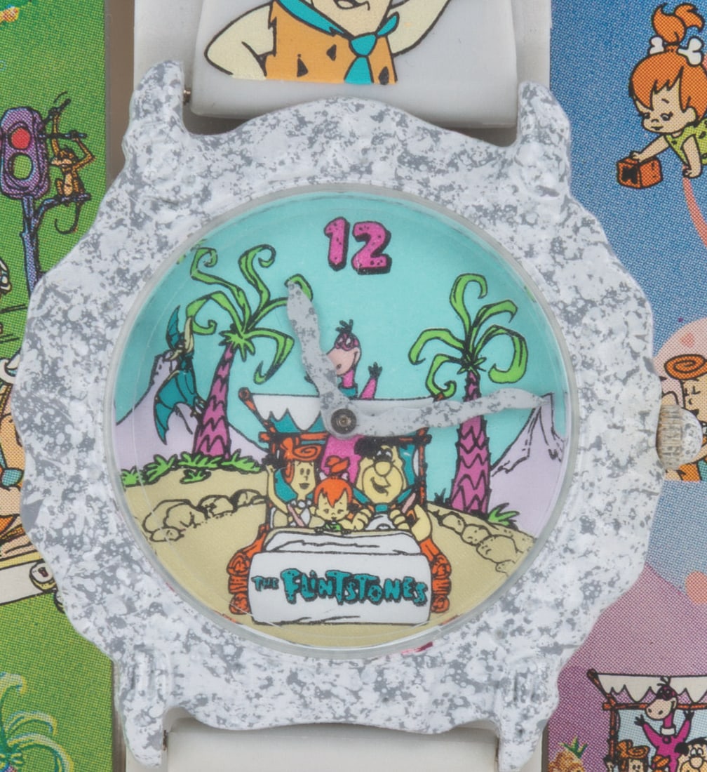 A "The Flintstones" Watch in Display Box.: (Innovative Time, 1991) A "The Flintstones" faux stone watch featuring the show's characters on the face, band, and box. The unused watch did not work when tested, likely requiring a new battery or