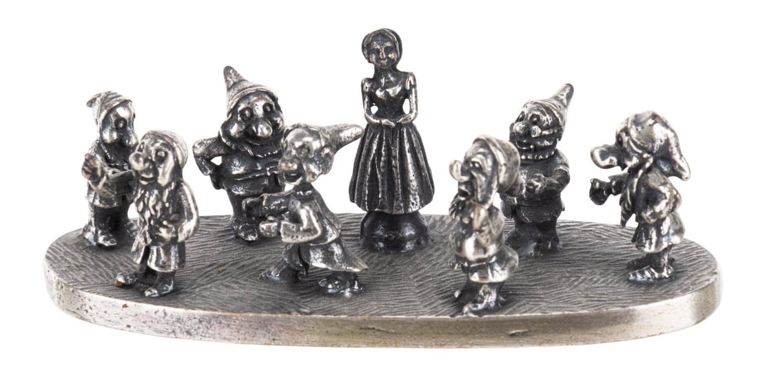 A Miniature "Snow White" Metal Figurine.: (Disney, 1970s-90s) A miniature "Snow White and the Seven Dwarfs" figurine featuring Snow White surrounded by the Seven Dwarfs. Measuring 1" x 2.75" x 1" tall, the metal piece is in very good