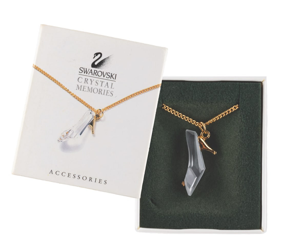 A Swarovski Crystal Memories Cinderella Shoe Necklace.: (Swarovski, 1990s) A Swarovski Crystal Memories necklace of Cinderella?s slipper. Witha 20" chain, the necklace is in fine condition. the original box is in very good condition with the interior foam