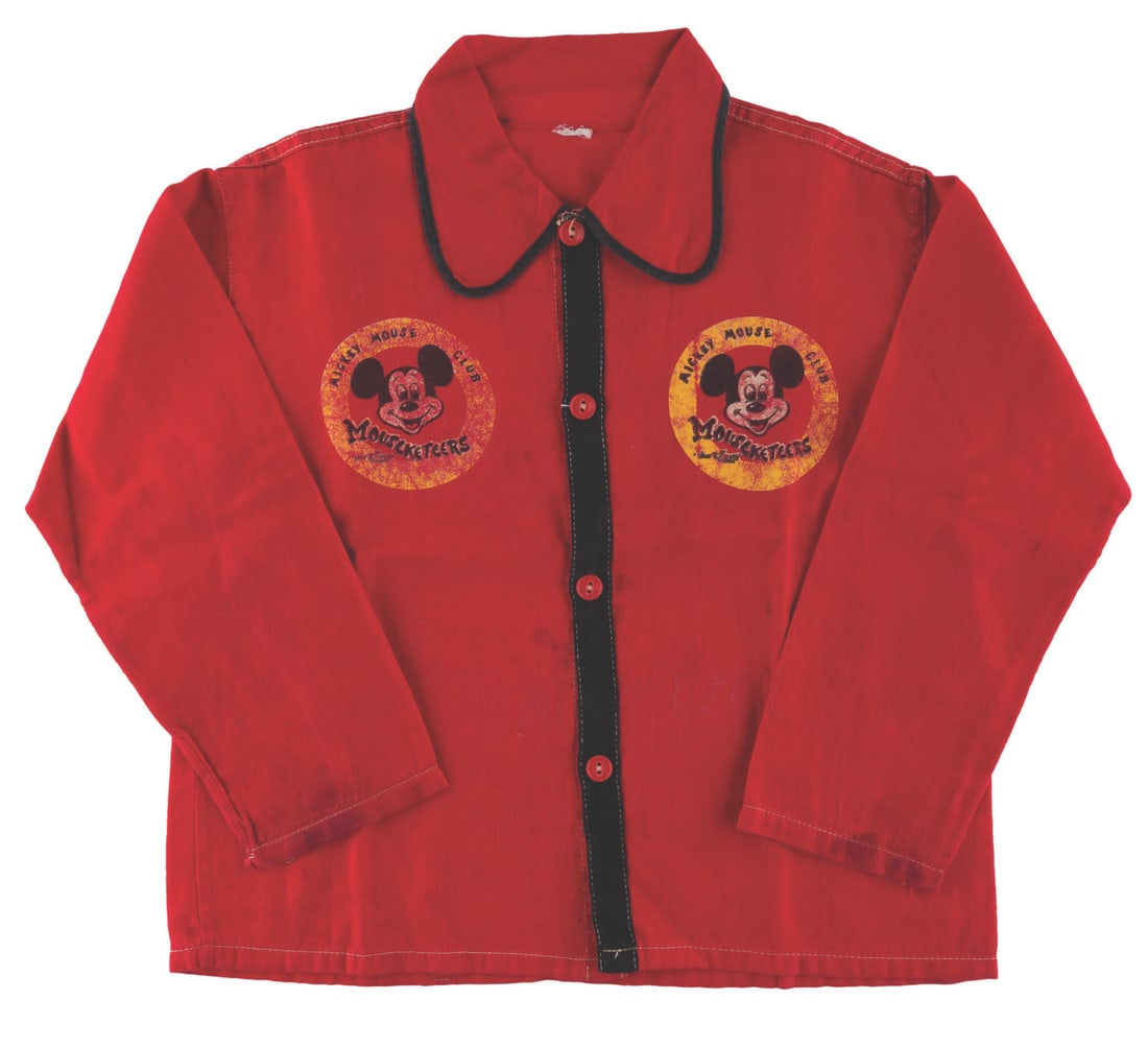 A Mickey Mouse Club Mouseketeer Child?s Shirt.: (Ben Cooper, 1950s) The shirt from a Ben Cooper Mickey Mouse Club play outfit. Measuring flat 19" tall x 17.5" wide with 15" sleeves, the shirt is in good condition with wear to the logos, light wear