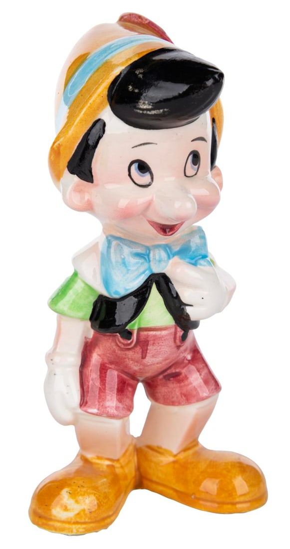 A Ceramic Pinocchio Figurine.: (Disney, 1970s-80s) A ceramic figurine of Pinocchio. Standing 5.25" tall, the figurine is in very good condition with light paint loss to the right side of the hair, and a tiny chip to the back of