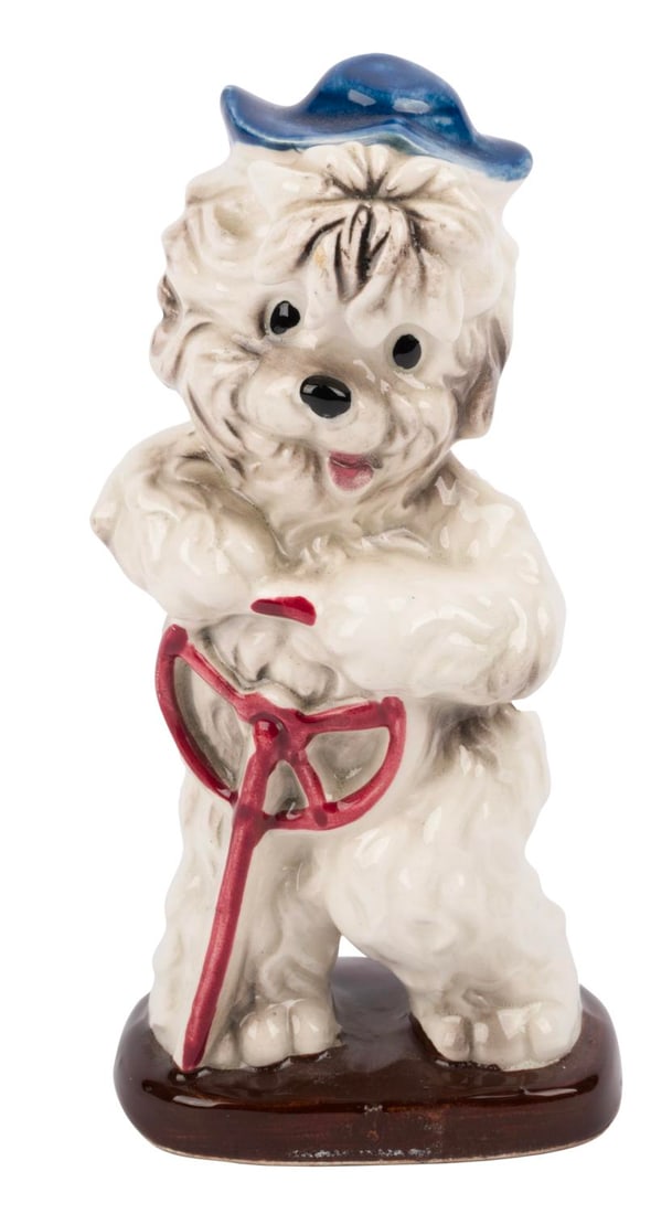 A "Shaggy Dog" Ceramic Figurine.: (Enesco, 1950s-60s) A ceramic figurine of "The Shaggy Dog." Measuring 1.5" x 2.5" x 5" tall, the figurine is in fine condition.