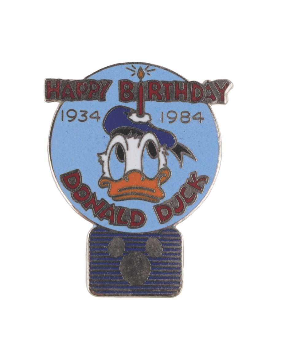 A Donald Duck 50th Birthday Disney Channel Pin.: (Disney, 1984) An enameled pin from the Disney Channel commemorating Donald Duck's 50th birthday in 1984. At the time, the fledgling cable channel was just over a year old, and the pin is displayed