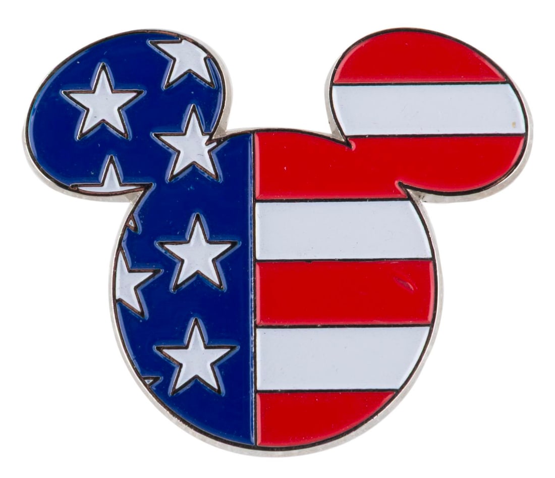 An American Flag Mickey Mouse Bolo Tie Clasp.: (Disney, 2000s) A Mickey Mouse head bolo tie clasp with an American flag pattern. Measuring 1.75" x 2", the metal bolo tie clasp is in good condition with scratches and wear.