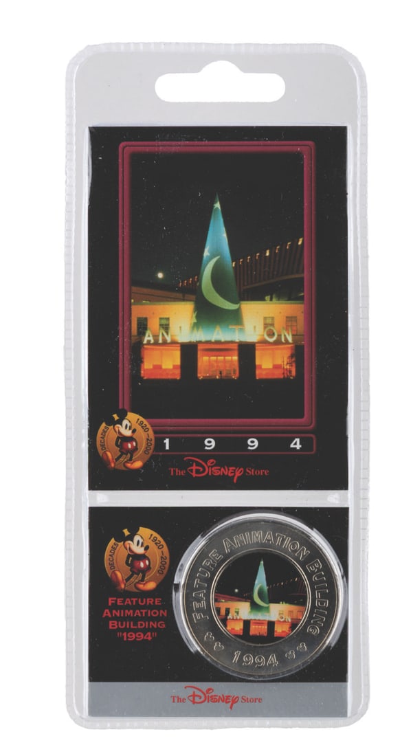 An Animation Building Disney Decades Commemorative Coin.: (Disney, 2000) A Disney Decades coin and collector card of the colorful Feature Animation Building that became an instant landmark in Burbank, California in 1994. The set is in fine condition sealed