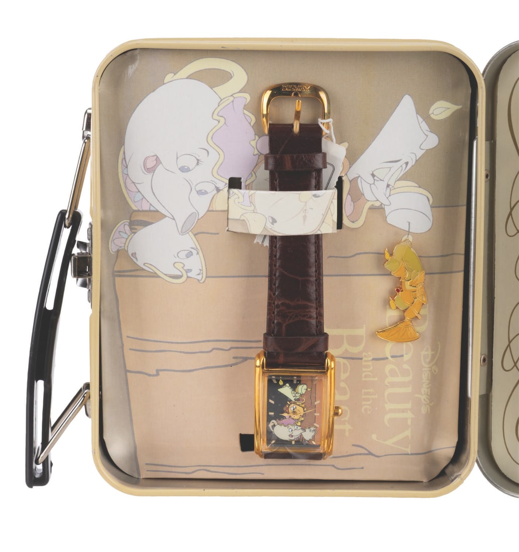 A "Beauty and the Beast" Lunchbox Watch Set.: (Disney, 1990s) A “Beauty and the Beast” watch and Lumiere pin in a tin lunchbox, released in a limited edition of 5,000. In the lunchbox measuring 2.25" x 5.5" x 4.75" high, the set is in