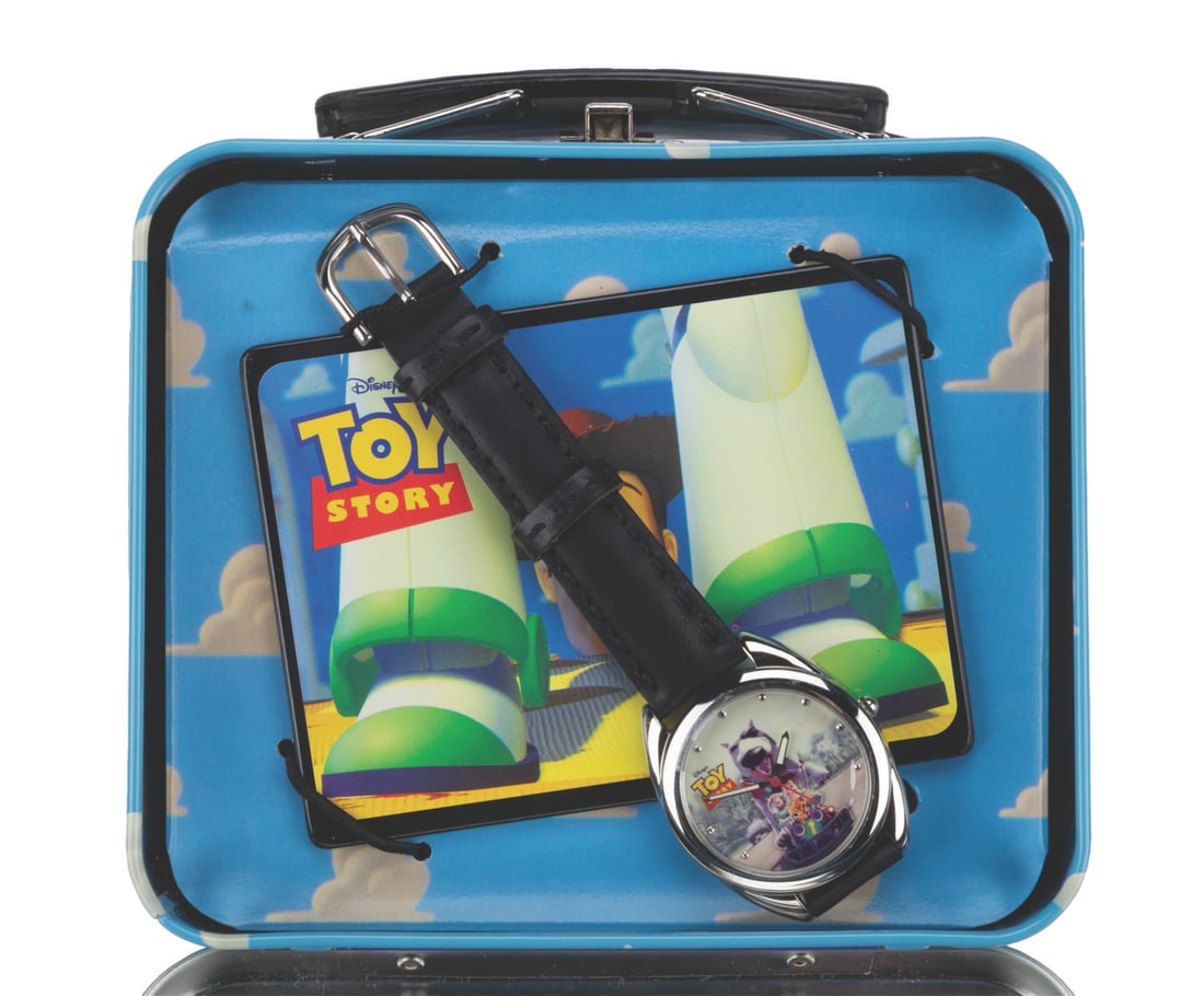 A "Toy Story" Watch in a Lunchbox.: (Disney/Fossil, 1996) A "Toy Story" watch, certificate of authenticity, and tin lunchbox. The watch is a limited edition of 10,000 with the "Toy Story" logo and a serial number on the back. The face f