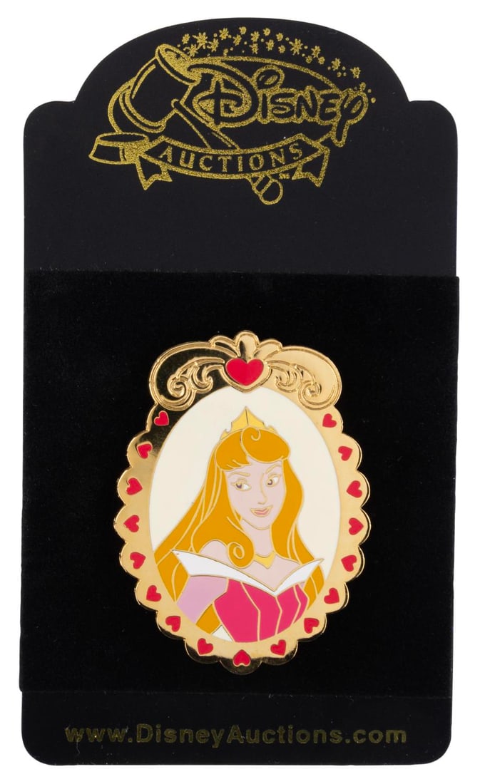 A Disney Auctions Aurora Cameo Pin.: (Disney, 2003) A Disney Auctions Princess Cameo Series pin of Aurora released in a limited edition of 250. Measuring 1.5" x 2" on its original 2.5" x 4.5" backing card, the pin is in fine condition.