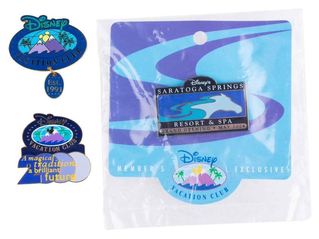 A Trio of Early Disney Vacation Club Pins.: (Disney Vacation Club, 2000s) Three early Disney Vacation Club pins. Included are a rare pin from the opening of the Saratoga Springs Resort and Spa, a logo pin with a dangle feature, and a magical