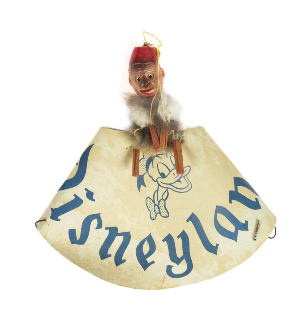 A Disneyland Souvenir Organ Grinder Monkey Hat.: (Disneyland, 1950s) A very rare early paper souvenir hat from Disneyland. The hat features an organ grinder monkey on top, complete with strings that pull its arms up and down. In the first few years