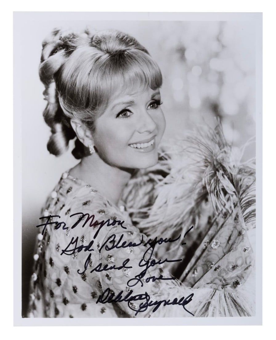 A Debbie Reynolds Signed Photograph.: (Reynolds, 1990s) An autographed photo of actress Debbie Renolds. Measuring 8" x 10", the photo signed with a dedication is in fine condition.