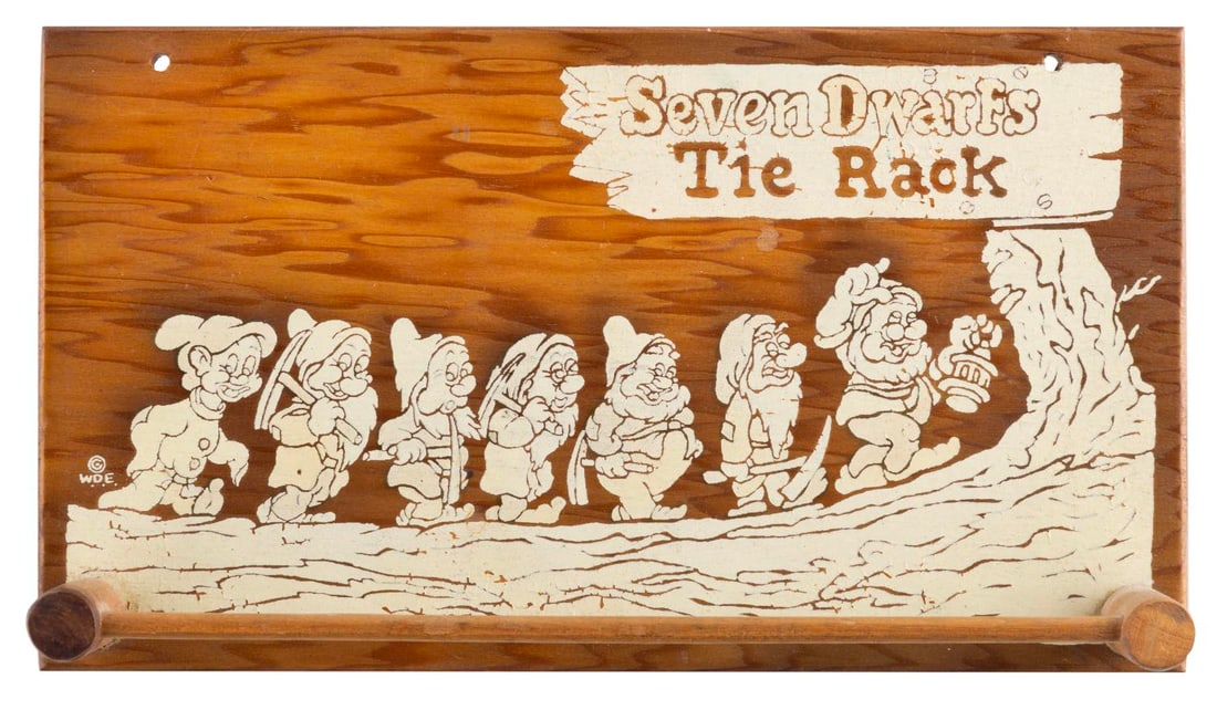 A "Snow White and the Seven Dwarfs" Tie Rack.: (Disney, 1930s-40s) A "Snow White and the Seven Dwarfs" wooden tie rack featuring the Dwarfs. Measuring 5" x 9", the tie rack displays in very good condition with paint cracks, scuffs, and wear.