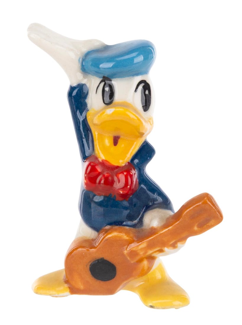 A Rare Donald Duck Ceramic Figurine.: (Shaw, 1940s-50s) A rare ceramic figurine of Donald Duck holding a guitar by Evan K. Shaw. Measuring 3" tall, the figurine is in good condition with crazing, chipping, spots of paint loss, and wear.