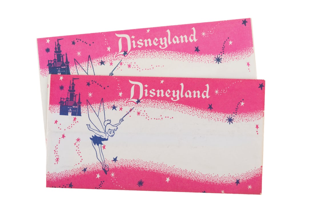 A Pair of 1960s Disneyland Envelopes.: (Disneyland, 1960s) A pair of pink envelopes featuring Tinker Bell and Sleeping Beauty Castle. Envelopes like these were used throughout the shops on Main Street, U.S.A., for smaller souvenir items, i