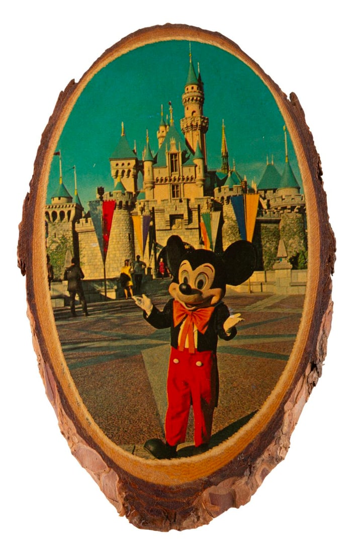 A Fan Made Mickey Mouse Wooden Plaque.: (Disneyland, 1960s-70s) A fan made wooden plaque with an image of Mickey Mouse in front of Sleeping Beauty Castle. Measuring 6.5" x 4", the honemade decoration is in good condition, with the bark on