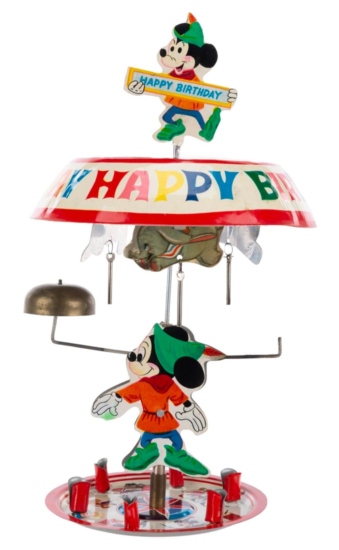 A Disneyland Tin Cake Topper Carousel with Box.: (Disneyland, 1960s) A tin happy birthday carousel featuring Disneyland characters, with the original box. When assembled, the heat from candles would spin the top, ringing the bells. Measuring 5" in