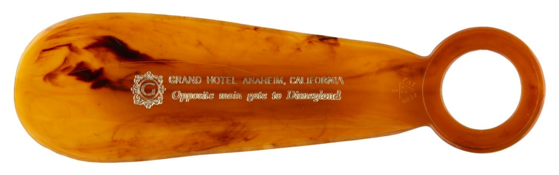 A Grand Hotel Anaheim Shoe Horn.: (Grand Hotel, 1960s-70s) A plastic shoe horn from the Grand Hotel in Anaheim, labeled with "Opposite main gate to Disneyland." Measuring 5.5" long the shoe horn is in very good condition with a few