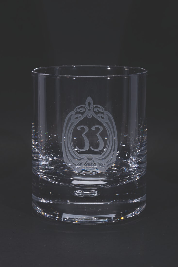 A Club 33 Rocks Glass.: (Disneyland, 2000s) A rocks glass featuring the logo of Disneyland's members-only restaurant Club 33. Measuring 4" tall and 3.25" in diameter, the glass displays in very good condition with scratches.