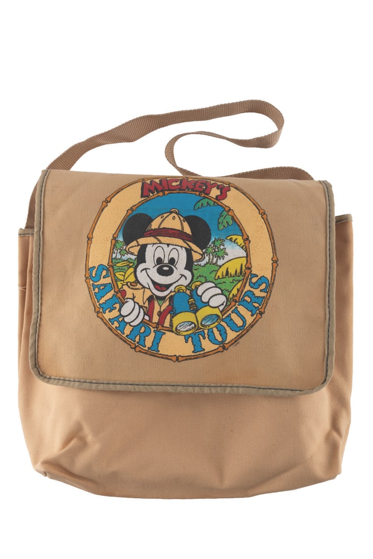 A "Mickey's Safari Tours" Canvas Bag.: (Disney Fashions, 1980s-90s) A canvas messenger bag featuring a "Mickey Safari Tours" logo. Measuring 6" x 12" x 12" tall, the bag is in very good condition with light discoloration, fading and