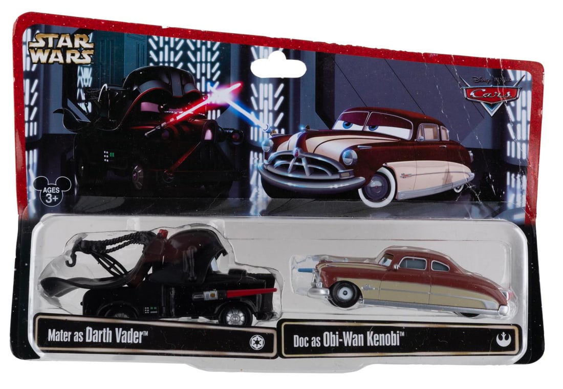 A Set of Cars/Star Wars Mashup Vader and Obi Wan Toys.: (Disney, 2013) A toy of Mater from "Cars" as Darth Vader, with Doc Hudson as Obi-Wan Kenobi. Measuring up to 4" long, the toys are in fine condition, still sealed on the original card. The card is in 