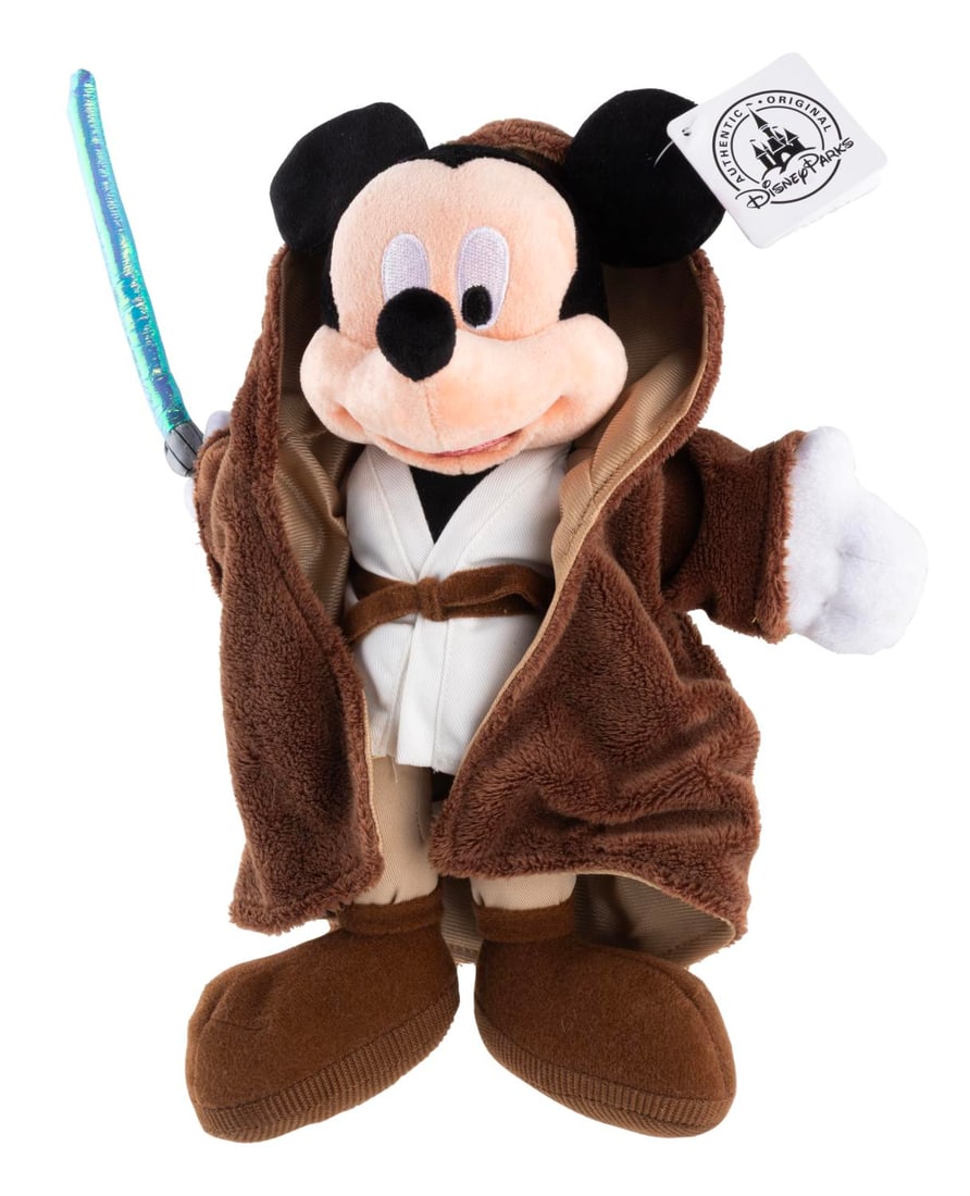 A Mickey Mouse Obi-Wan Kenobi Plush.: (Disney Parks, 2000s) A plush of Mickey Mouse dressed as Obi-Wan Kenobi from Star Wars, originally sold in the Disney Parks. Measuring 12" tall, the plush is in fine condition with its original tag.