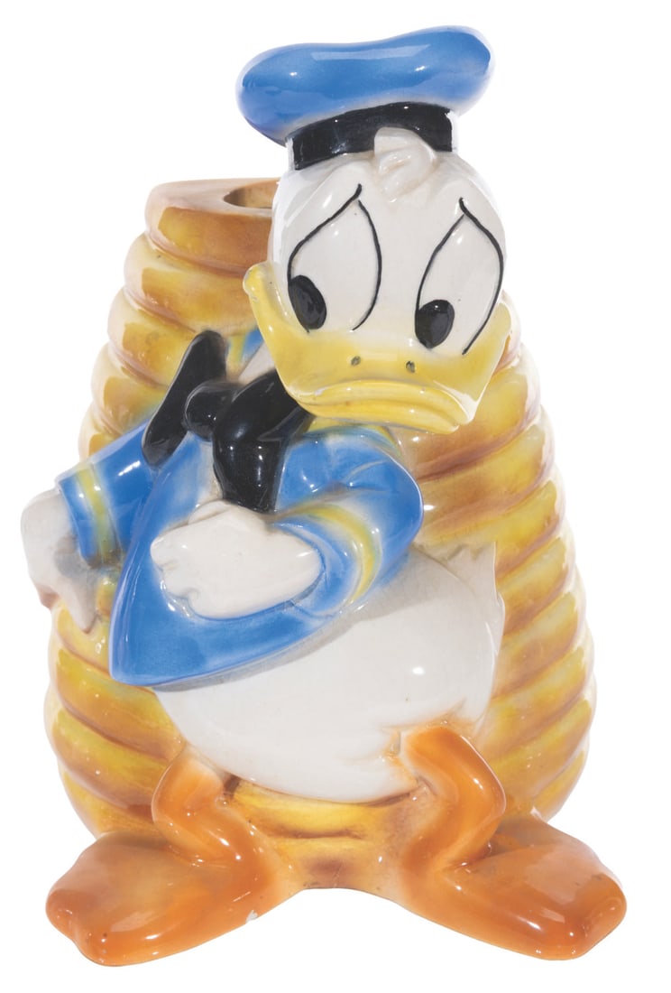 A Donald Duck Lamp Base.: (1950s-60) A lamp base featuring Donald Duck in front of a honeycomb. Measuring 4.5" x 4.5" x 7" tall, the ceramic lamp base is in good condition with crazing, chipping, spots of paint loss, wear, and