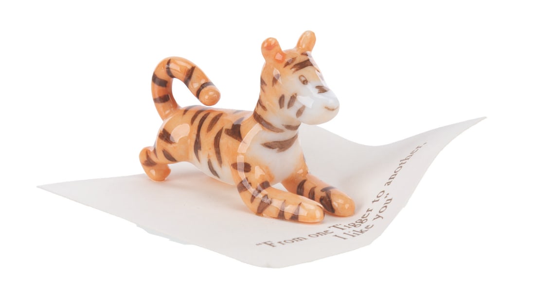 A Mini "Winnie the Pooh" Tigger Figurine.: (Michel and Co., 1990s) A mini ceramic figurine of Tigger, inspired by the original illustrations for the Winnie the Pooh books by E. H. Shepard. The figurine is attached to a card with a quote that r