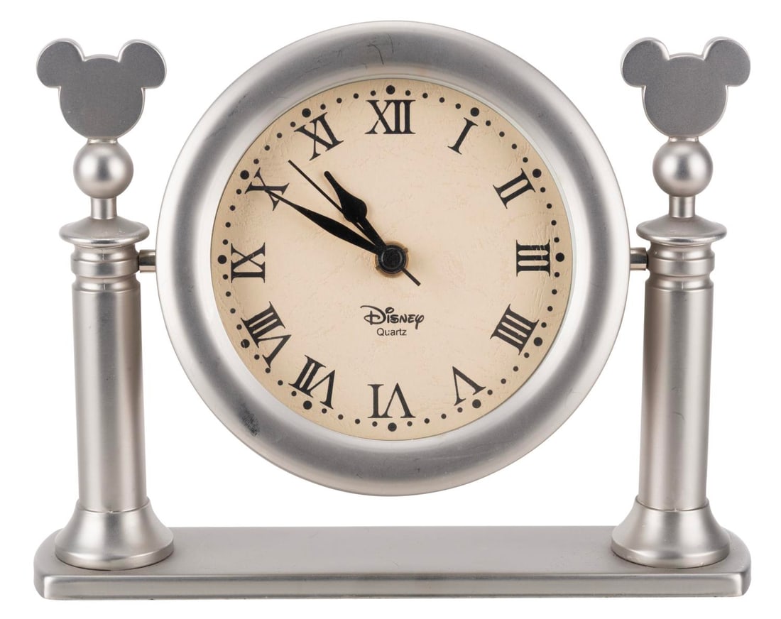A Mickey Mouse Mantle Clock.: (Disney, 1990s-2000s) A Mickey Mouse mantle clock. The metal and glass clock operates on one "AA" battery and functioned when tested. Measuring 1.75" x 7.5" x 9" the clock is in good condition with