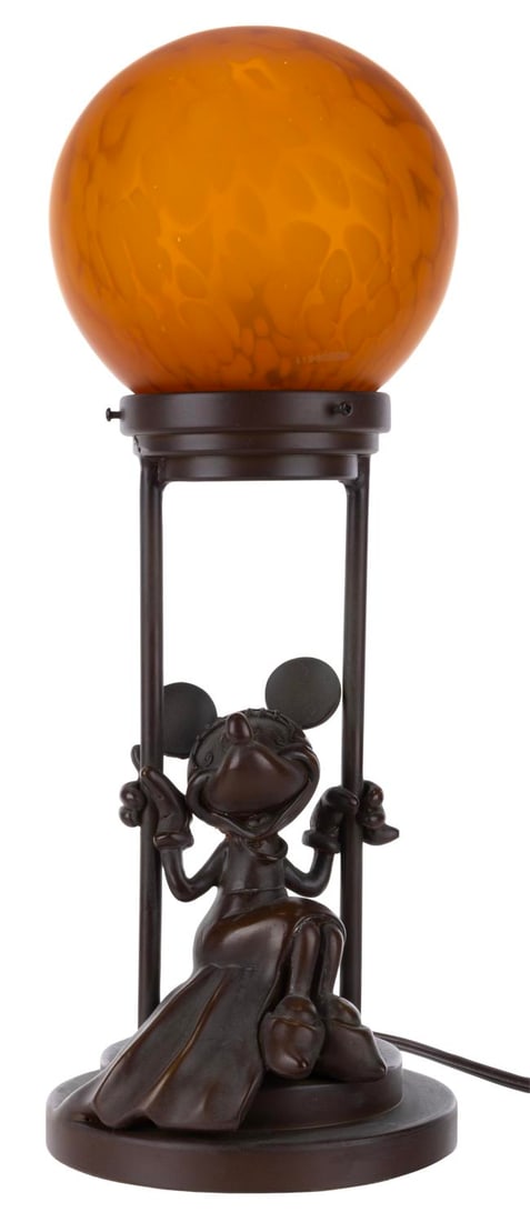 A Minnie Mouse Bronze Lamp.: (Disney, 2000s) A bronze lamp of Minnie Mouse, with an ornate orange bulb on top. The lamp did not work when tested, likely requiring repair to function. Measuring 15" tall and 6" in diameter, the lam