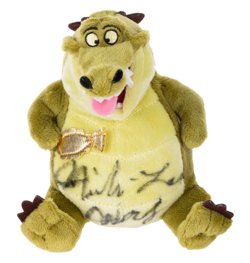 A Signed "The Princess and the Frog" Louis Plush.: (Disney, 2009) A plush of the trumpet-playing alligator Louis from "The Princess and the Frog," signed by the character's voice actor, Michael-Leon Wooley. Measuring 7.25" tall, the plush is in very g