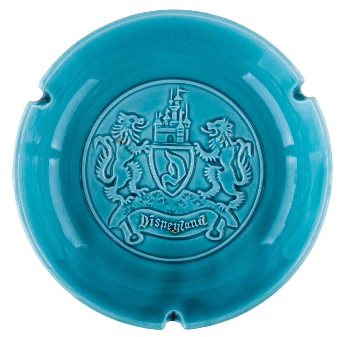 An Early Disneyland Crest Ashtray.: (Disneyland, 1950s) An early souvenir of Disneyland ashtray featuring the official crest of the Park at its center. Measuring 6.25" in diameter, the ashtray is in very good condition with a few tiny
