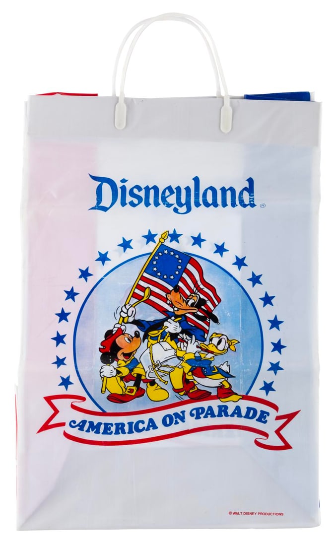 A Rare Disneyland America on Parade Plastic Bag.: (Disneyland, 1976) A rare plastic America on Parade merchandise bag from Disneyland's bicentennial celebration. The bag features a flat cardboard bottom and plastic snaps to close the top. Measuring 5