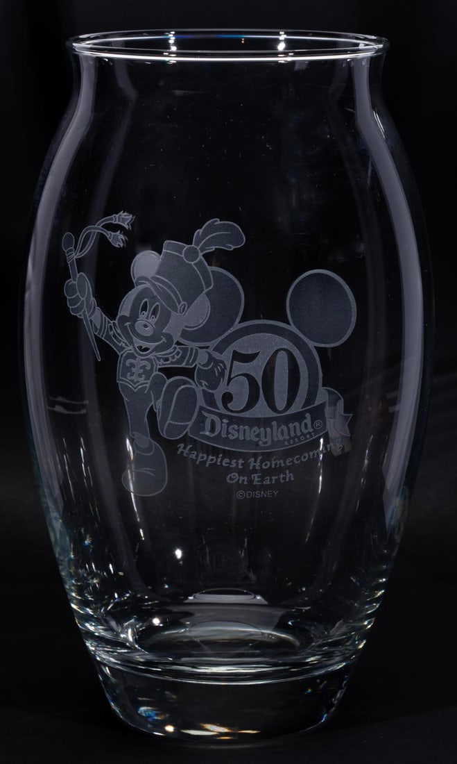 A Disneyland 50th Anniversary Vase.: (Disneyland, 2005) A Disneyland 50th anniversary glass vase etched with Mickey leading the parade of "The Happiest Homecoming on Earth." Measuring 5" in diameter x 8.5" tall, the vase is in fine