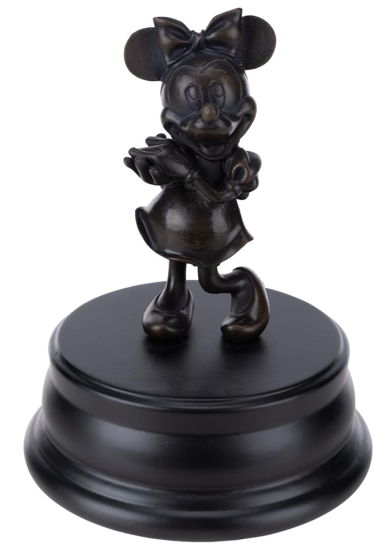 A Minnie Mouse Bronze Statue.: (Disney, 2000s) A bronze replica of the Minnie Mouse statue on display in front of Sleeping Beauty Castle at Disneyland. Measuring 6.5" tall and 5" in diameter, the statue is in very good condition wi